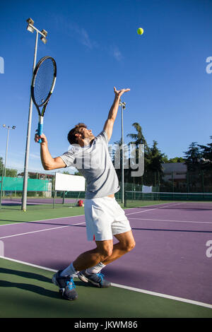 Profi-Tennisspieler tut ein Kick-Tennis auf dem Tennisplatz an einem sonnigen Sommermorgen. Stockfoto