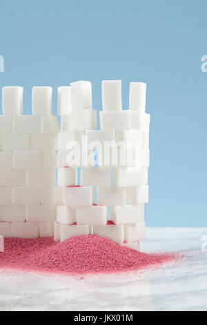 Eine Burg mit Zuckerwürfel und rosa Sand zu seinen Füßen. Minimal und lustigen Design Still Life Fotografie. Stockfoto