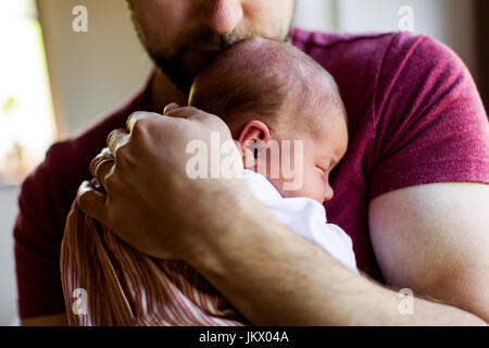Nicht erkennbare junger Vater zu Hause hält sein neugeborenes gir Stockfoto