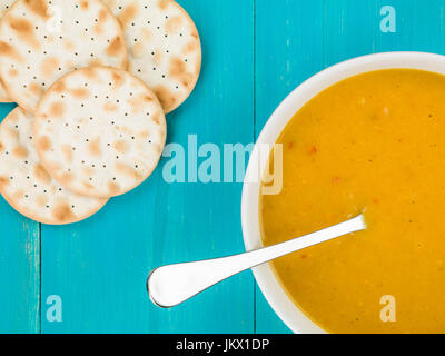 Schüssel mit Butternut-Kürbis-Süßkartoffel Suppe auf blauem Grund aus Holz Stockfoto
