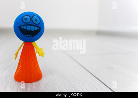 Blau und orange Spielzeug Smiley auf dem Boden Stockfoto