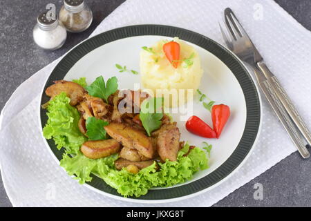 Fried Bull Hoden mit Sahne und Kräutern serviert mit Kartoffelpüree auf einem weißen Teller vor einem abstrakten Hintergrund. Gesunde Ernährung-Konzept. Stockfoto