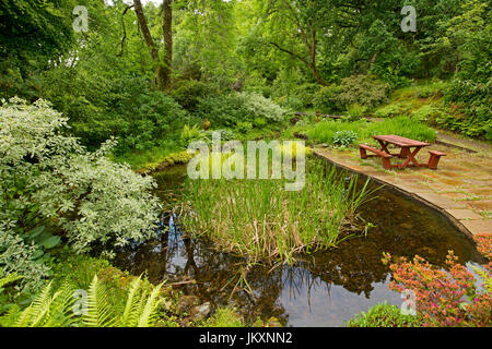 Spektakuläre Gemeinschafts-Garten mit Wasserspiel, Pflasterarbeiten, Picknick-Tisch und Bäume spiegeln sich im Wasser des ruhigen Pool - in Schottland Stockfoto