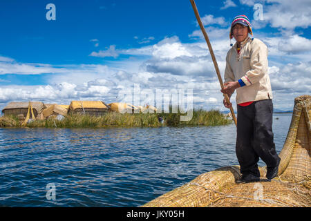 UROS-Inseln, PERU - ca. APRIL 2014: Mann von den Uros Inseln im Titicaca-See Rudern in typischen Kanu von Totora-Schilf gemacht. Stockfoto