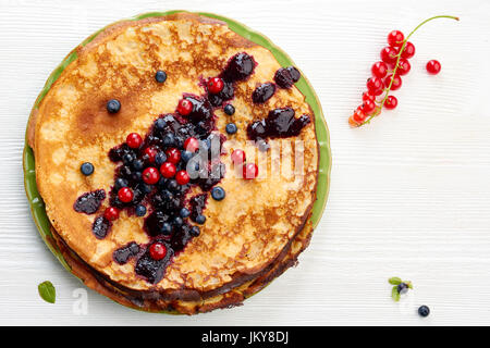 Dünne Pfannkuchen mit Sommerbeeren auf weißer Holztisch Stockfoto