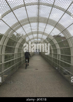 Mädchen in schwarz Fahrradtouren in einen Tunnel über eine Autobahn in Brooklyn New York. Alternative Verkehrsmittel, Autos, Reiten eine Fahrradstadt an einem trüben Tag im Stockfoto