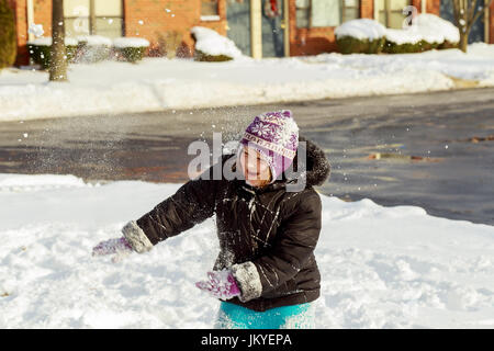 Kleines Mädchen Schneeschaufeln auf Basislaufwerks Weg. Schönen verschneiten Garten oder Vorgarten. Kind mit Schaufel spielen im Freien in der Wintersaison. Familie removi Stockfoto