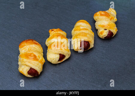 Hausgemachte Schweine in eine Decke. Würstchen gerollt in Croissant-Teig, gebacken, Kühlung auf Metallgestell. Stockfoto