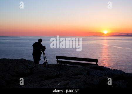 Mann-Fotografen Fotografieren von Sonnenuntergang am Meer. Stockfoto