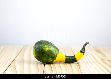 Ein dekorativer Kürbis (Crookneck Squash) auf Holz liegend mit Hintergrund für einen text Stockfoto