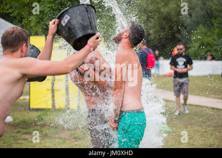 BONTIDA, Rumänien - 16. Juli 2017: Lustiger Kerl Spours Wasser aus einem Eimer am Kopf Freund bei elektrischen Schlossfest Stockfoto