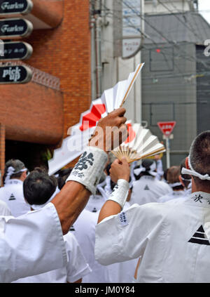 KYOTO, JAPAN - 24. Juli 2017: Zwei Männer Welle Fans mit steigenden Sonnen auf ihnen, wie sie als Teil des Gion Matsuri in Kyoto, Japan parade Stockfoto