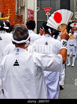 KYOTO, JAPAN - 24. Juli 2017: Wellen ein Mann einen weißen Lüfter mit einer aufgehenden Sonne drauf, wie er während der Gion Matsuri in Kyoto, Japan Paraden Stockfoto