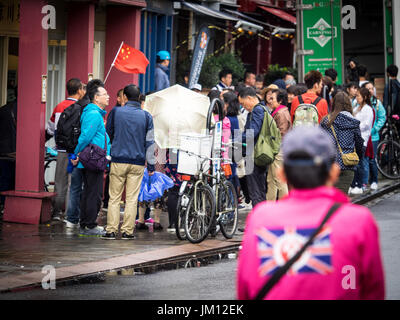 Chinesische Touristen Cambridge - Parteien der chinesischen Touristen mit Guide mit Kennzeichnung Flagge im historischen Zentrum von CAMBRDIGE UK Stockfoto