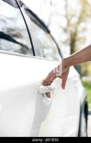 Teilansicht der Frau Türöffnung Auto auf dem Parkplatz Stockfoto