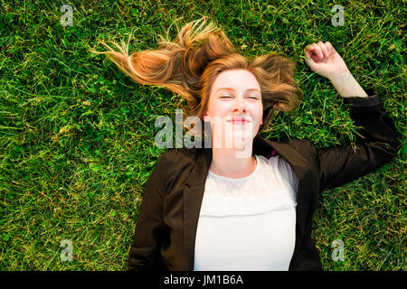 junge unabhängige Frau entspannen auf dem Rasen im park Stockfoto