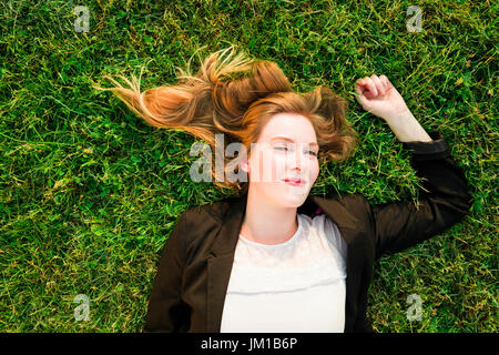 junge unabhängige Frau entspannen auf dem Rasen im park Stockfoto