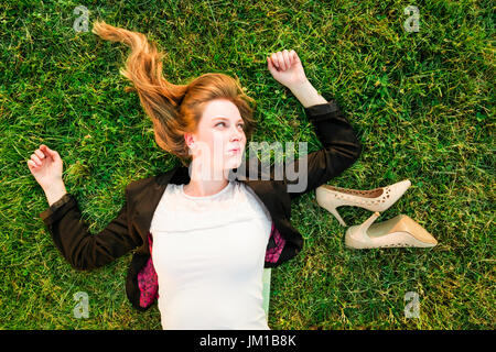 junge unabhängige Frau entspannen auf dem Rasen im park Stockfoto