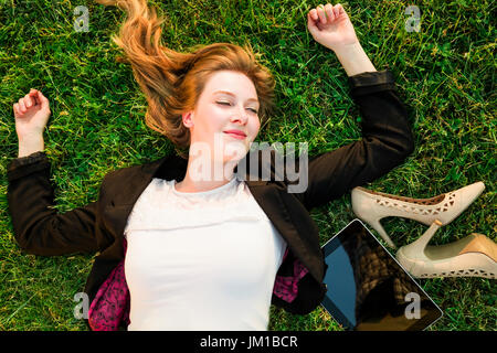 junge unabhängige Frau entspannen auf dem Rasen im park Stockfoto