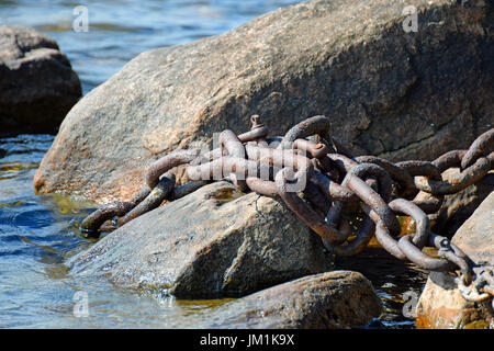 Alten rostigen Eisenkette auf Steinen und Wasser. Stockfoto