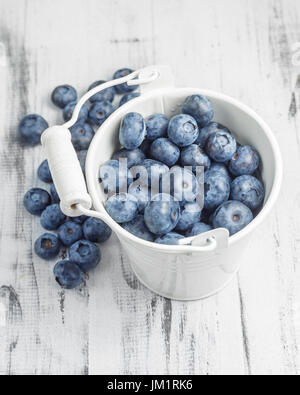 Heidelbeeren in weißen Blecheimer auf weißem Holz Hintergrund Stockfoto