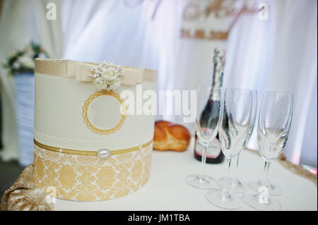 Schön dekorierten Box auf der Hochzeitstafel neben dem Champagner-Flasche und Gläser. Stockfoto