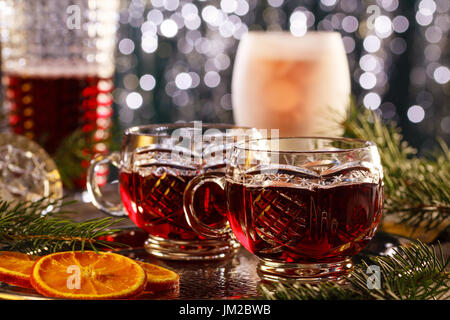 Heißer Glühwein auf dekorative Gläser mit Scheiben von Orange in weihnachtlicher Atmosphäre. Stockfoto