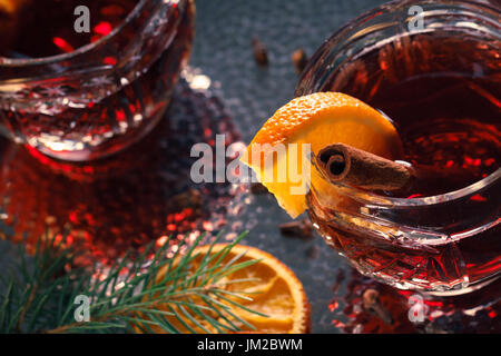 Heißer Glühwein auf dekorative Gläser mit Scheiben von Orange in weihnachtlicher Atmosphäre. Stockfoto