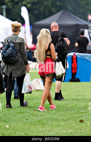 Mädchen im roten Shorts mit tätowierten Beine kommen bei einem Outdoor-Musik-Festival mit einem männlichen Freund Stockfoto