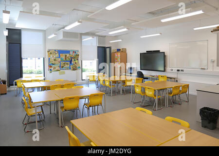 Innenraum eines Klassenzimmers in einer neu errichteten Grundschule im Osten Londons, Großbritannien. Zeigt Schreibtische, Stühle und großen TV-Bildschirm.leer, keine Schüler. Stockfoto