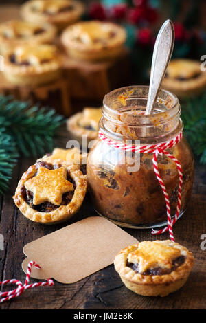 Traditionelle festliche Weihnachten Mince Pies mit ein Glas hausgemachte Hackfleisch und ein leeres tag Stockfoto