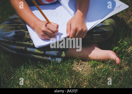 Eine Jugend schreibt in einem Notebook für Schulbildung zurück in die Schule zu lernen. Stockfoto