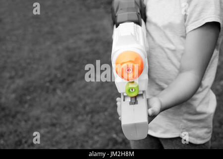 Ein Kind hält eine Spielzeugpistole Wasser in Händen, selektive Farbbild Stockfoto