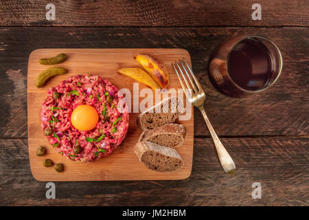 Steak Tartar mit Beilage, Rotwein und Exemplar Stockfoto