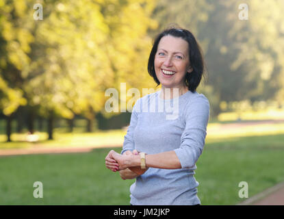 Porträt von Reife Frau Cheking den Puls nach Joggen im Park. Attraktiv aussehende Reife Frau halten Fit und gesund. Stockfoto