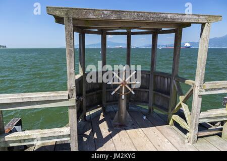 Schiffsrad und hölzerne Quay-Struktur am Strand des Anlegekais von New Mexico mit Blick auf den Burrard Inlet und die Pazifikküste in Vancouver, BC, Kanada Stockfoto