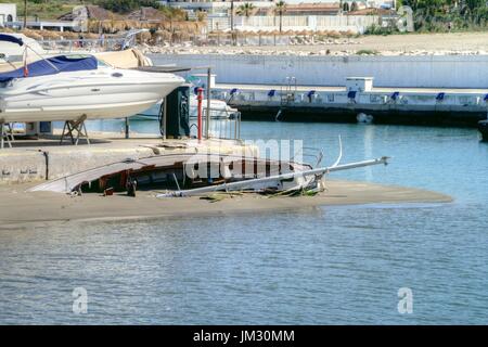 Gesunkenes Segelboot gefangen im Sand nach einem Sturm am Eingang zum Hafen von Cabopino. Stockfoto