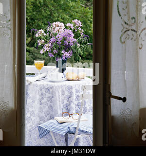 Blick auf Blumen-Arrangement und Tabelle durch Tür Stockfoto