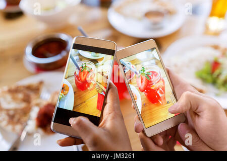 Hände mit Getränken auf Smartphones im restaurant Stockfoto