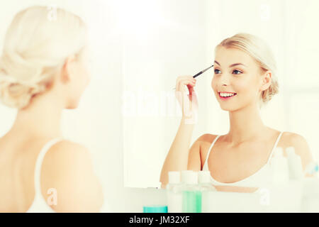 Frau mit Pinsel Augenbrauen Make-up im Badezimmer zu tun Stockfoto