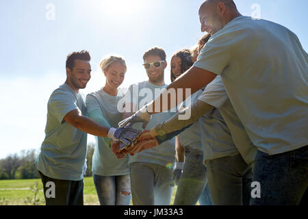 Gruppe von Freiwilligen, die oben im freien Hände aufsetzen Stockfoto