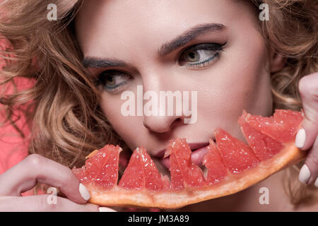 Porträt der Frau hält Stück isoliert auf rosa grapefruit Stockfoto