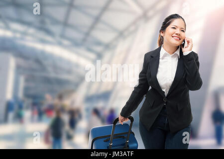 Geschäftsfrau, telefonieren mit Handy während Gepäck im Flughafen Stockfoto