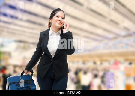 Geschäftsfrau, telefonieren mit Handy während Gepäck im Flughafen Stockfoto