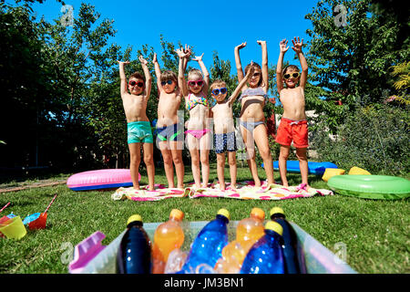 Gruppe von Kindern im Badeanzug mit im Sommer erhobenen Armen. Stockfoto