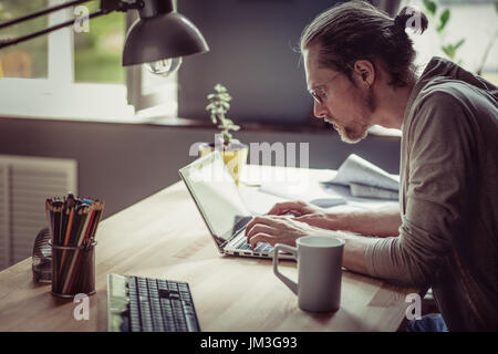 Freiberufler schreiben und arbeiten mit Laptop. Mann arbeiten selbständig zu Hause ernsthaft auf der Suche im Computer. Stockfoto