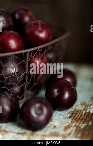 Reife Pflaumen in einem Korb auf einem hölzernen Hintergrund. Makro-Foto. Selektiven Fokus. Stockfoto