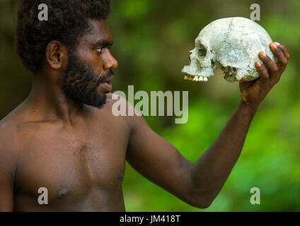 Mann hält einen menschlichen Schädel in Amelbati Kannibale Website, Provinz Malampa, Malekula Insel, Vanuatu Stockfoto