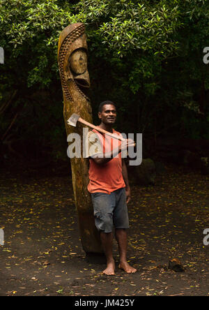 NI-Vanuatu Mann mit einer Axt vor einem Schlitz Gong drum im Dschungel, Insel Ambrym, Olal, Vanuatu Stockfoto