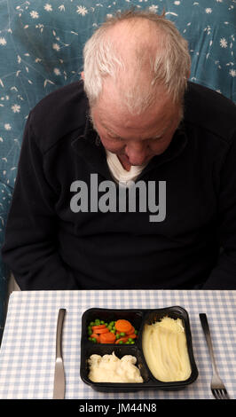 Älterer Mann blickte auf seine Mikrowellen Fertiggerichte Stockfoto